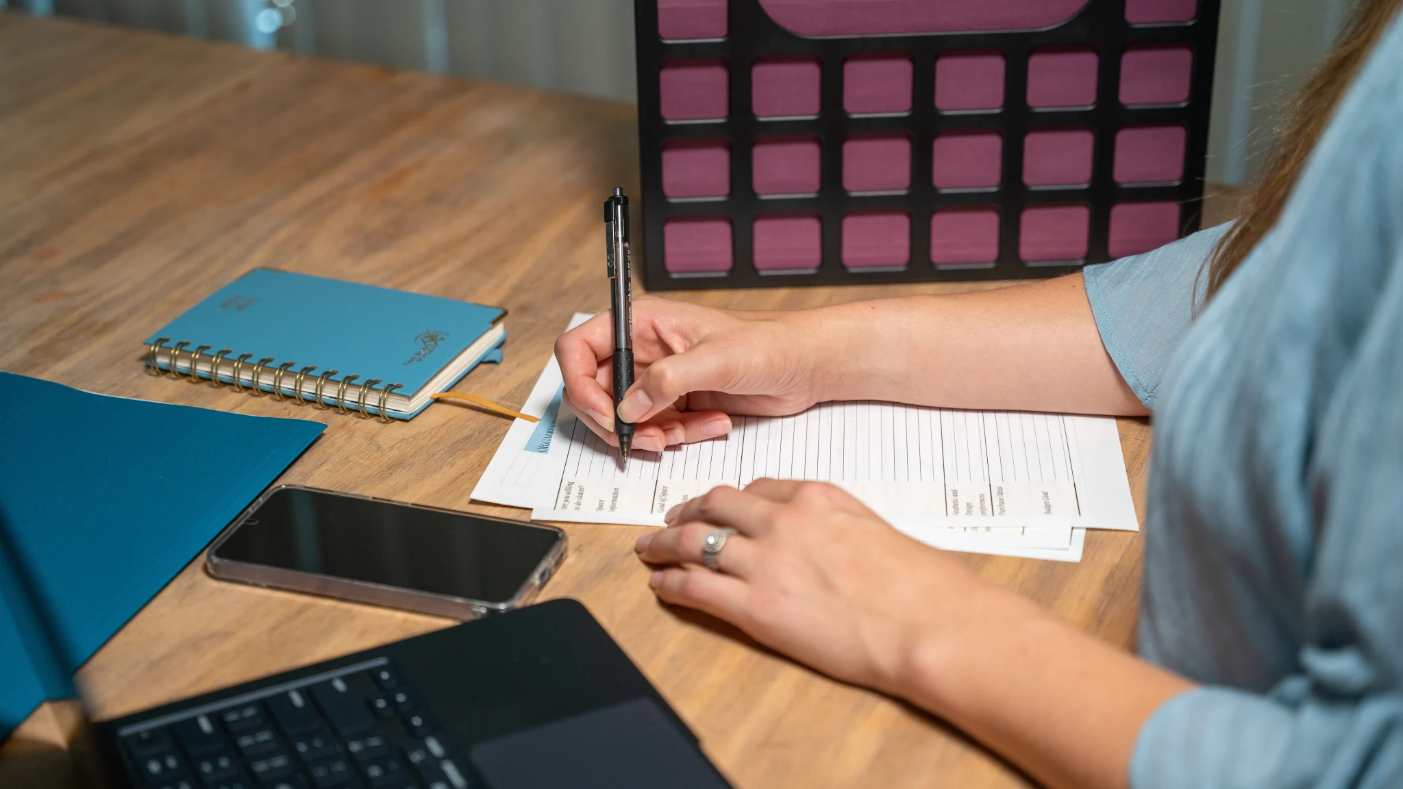 Professional organizer writing on documents at desk with notebook and laptop