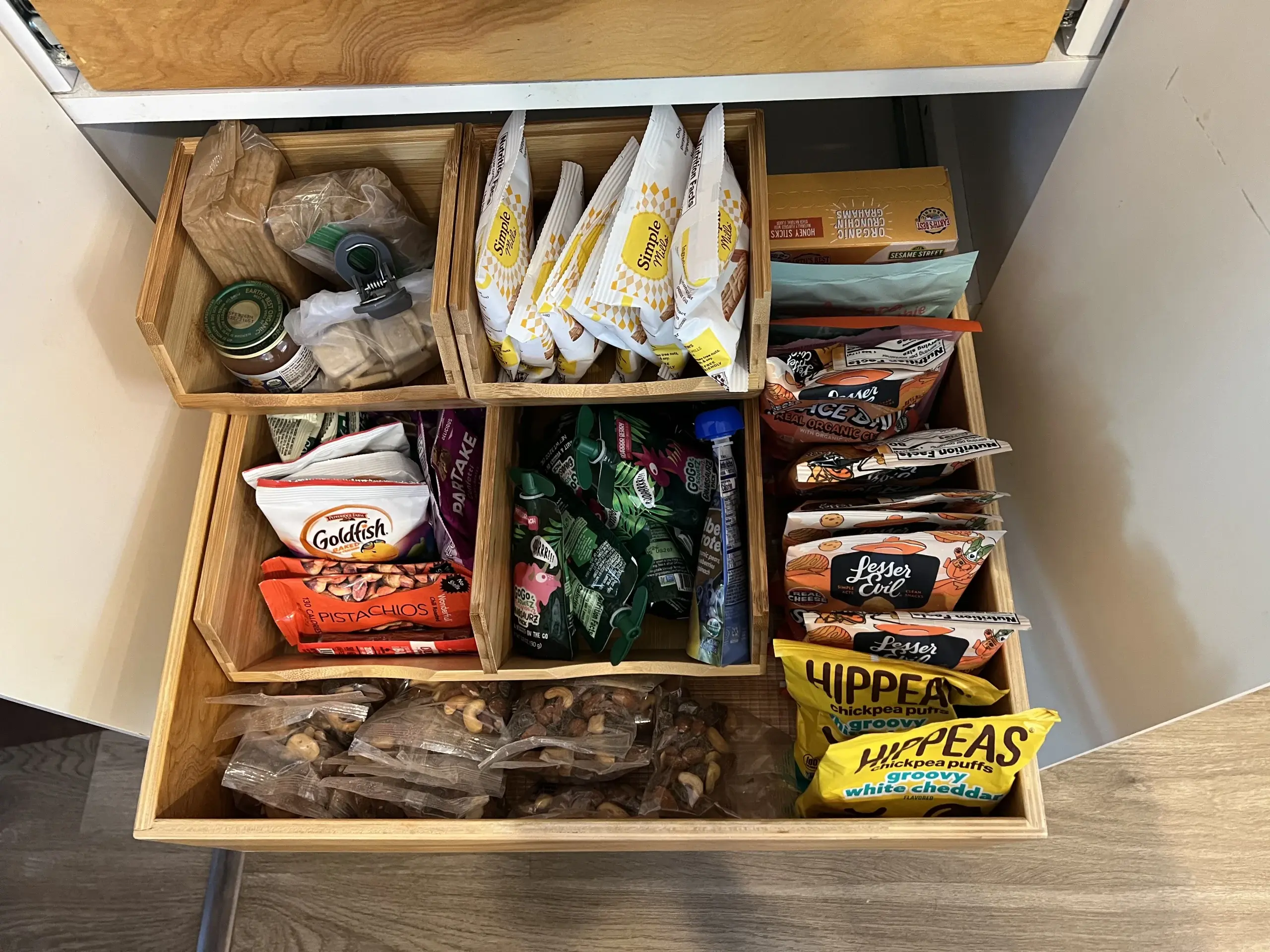 Neatly organized snack drawer with wooden dividers and labeled sections
